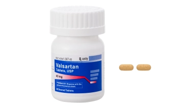 Image of a bottle of valsartan tablets and two tablets outside of the bottle.